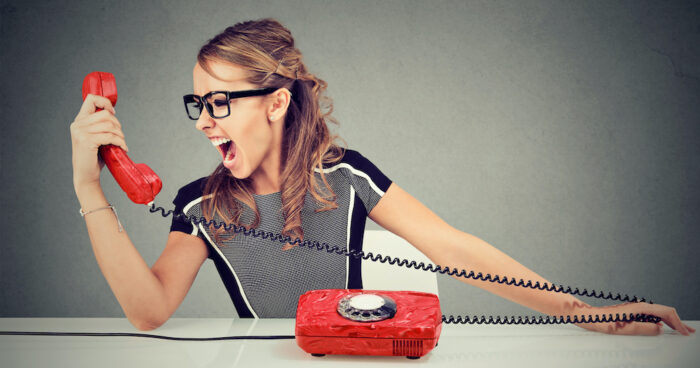 Woman looking at red telephone with an angry face.