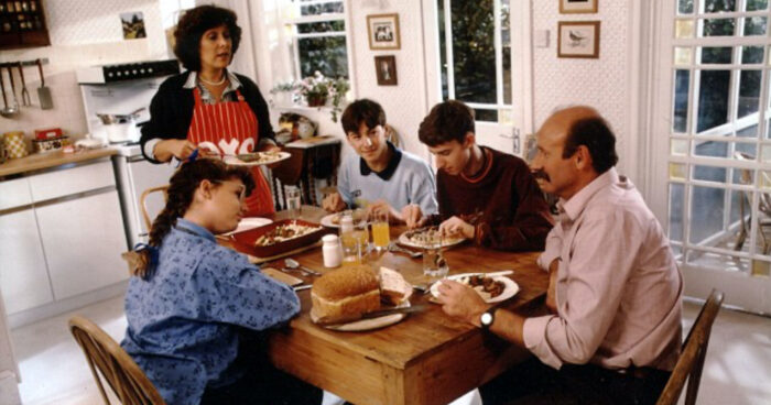 Picture shows the Oxo family Christmas commercial with the family sitting around a kitchen table.